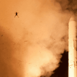 a rocket launching, there's fire and smoke, and the silhouette of a frog being thrown into the air