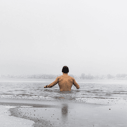 A man topless in a cold lake.